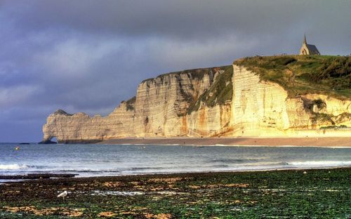 Scenic view of sea by cliff against sky