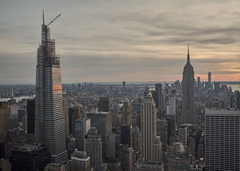 Aerial view of buildings in city against cloudy sky