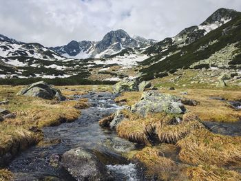 Scenic view of stream amidst mountains against sky