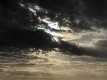 Low angle view of sunlight streaming through clouds