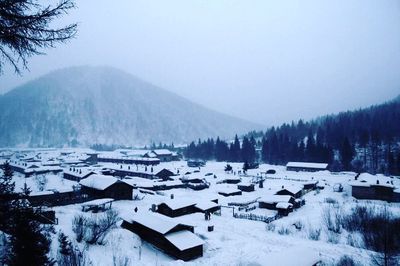 Snow covered land and houses against sky