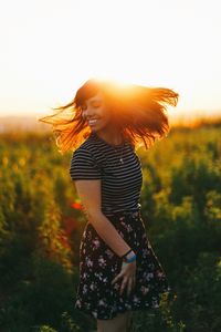 Cheerful young woman tossing hair while standing on field