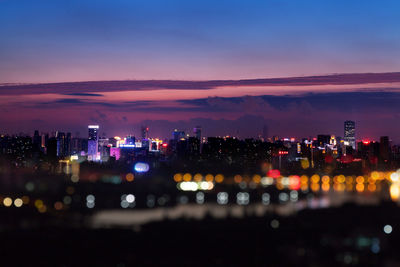 Illuminated cityscape against sky at dusk