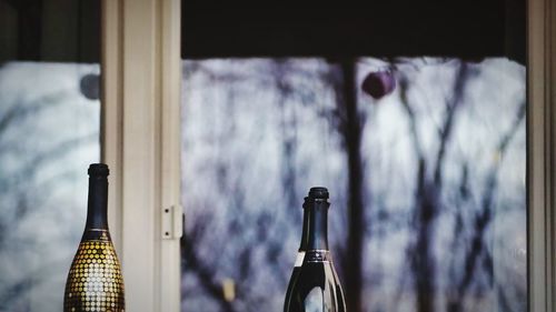 Close-up of champagne bottles in front of glass window