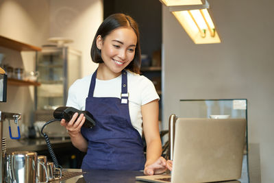 Portrait of young woman using phone while sitting in office