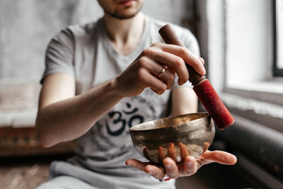 A male yogi plays a musical instrument singing bowl 