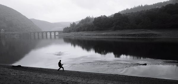 Man standing by lake against sky