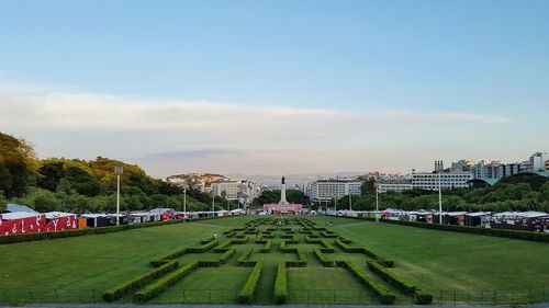 Park by buildings in city against sky