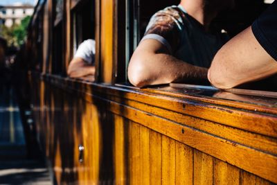 Cropped hands of people traveling in train seen through window