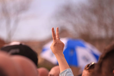 Rear view of woman showing peace sign amidst crowd 