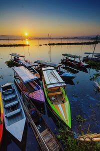 Boats moored in calm lake at sunset