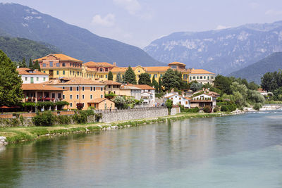 Buildings by lake and mountains against sky