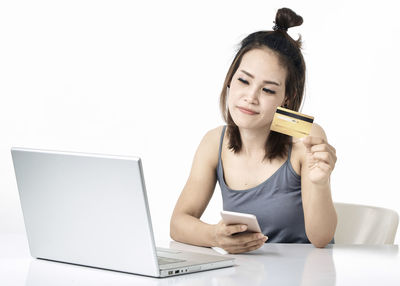 Young woman using phone while sitting on table