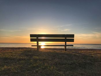Lifeguard hut on beach against clear sky during sunset