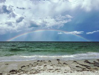 Scenic view of sea against rainbow in sky