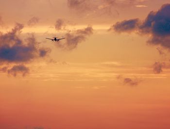 Low angle view of silhouette airplane against sky during sunset