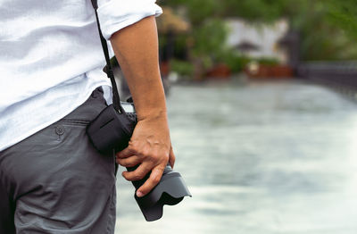 Midsection of man with camera outdoors