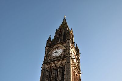 Low angle view of clock tower against blue sky