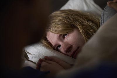 Crying young woman lying in bed
