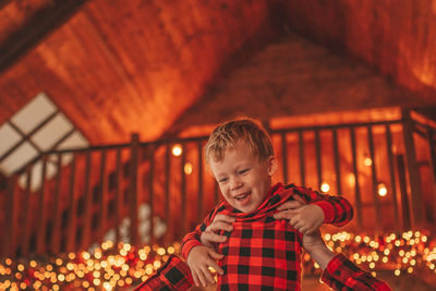 Candid authentic happy dad and son in red plaid pajamas fooling around at wood lodge xmas decorated