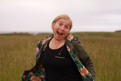 Portrait of woman standing on field against sky