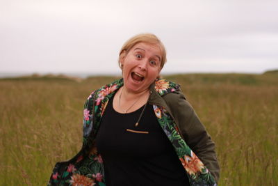 Portrait of woman standing on field against sky