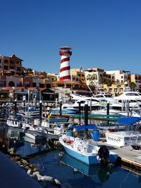 Boats moored at harbor against clear blue sky