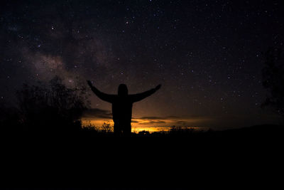 Silhouette man standing on field against sky at night
