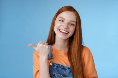 Woman showing thumbs up gesture against blue background