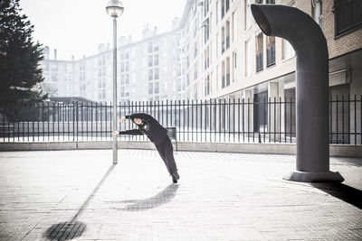 Woman dancing on footpath in city