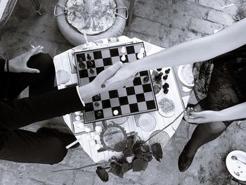 Low section of friends shaking hands over chess board in restaurant