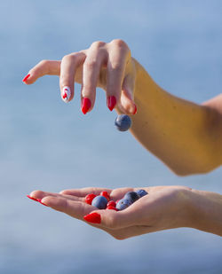 Cropped woman with berry fruits against clear sky