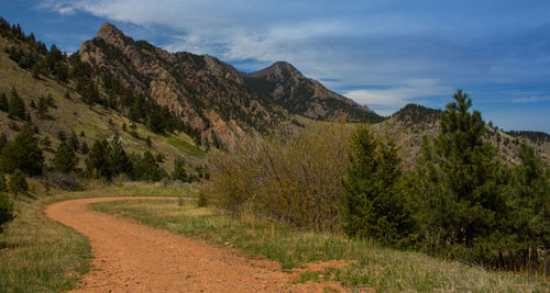 Scenic view of road by mountains against sky