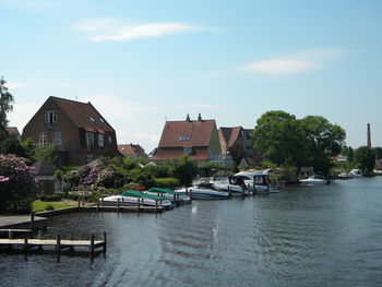 Boats moored on lake by houses