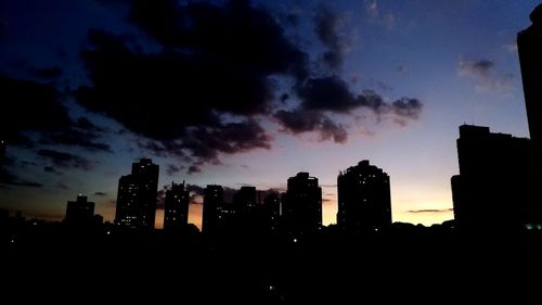 Silhouette buildings against sky at sunset