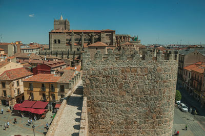 People walking on alley and pathway over wall with cathedral of avila. spain.