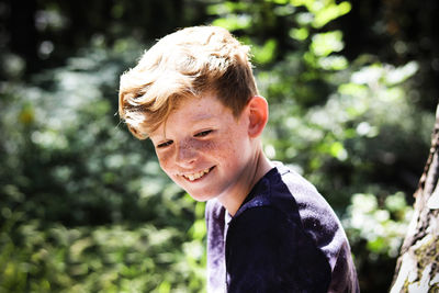 Smiling boy looking down in sunny day