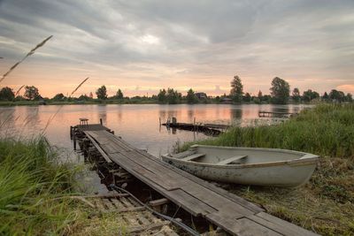 Boats moored in lake against sky during sunset