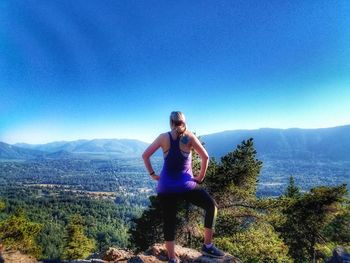Full length of young woman on mountain against clear blue sky