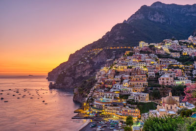 Scenic view of sea and buildings against sky during sunset