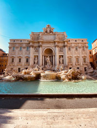 Statue of fountain in city against blue sky