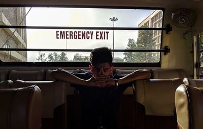 Portrait of teenage boy with hands clasped traveling in bus