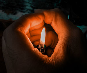 Close-up of hand holding lit candle