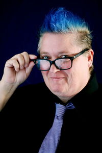 Close-up portrait of man wearing eyeglasses against black background