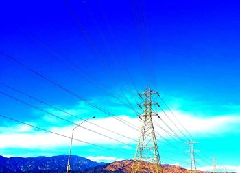 Low angle view of power lines against blue sky