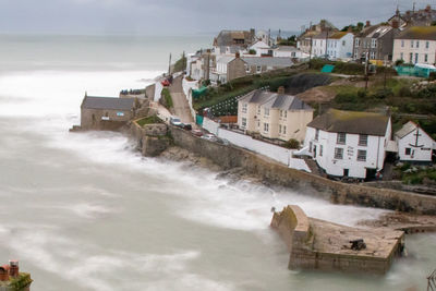 Houses by sea against sky in city