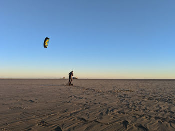 Woman kiteboarding at beach against clear sky