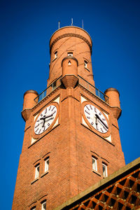 Low angle view of clock tower against clear blue sky