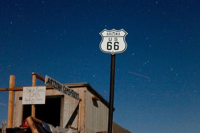 Low angle view of road sign against blue sky