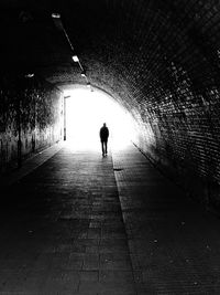 Rear view of silhouette man walking in tunnel